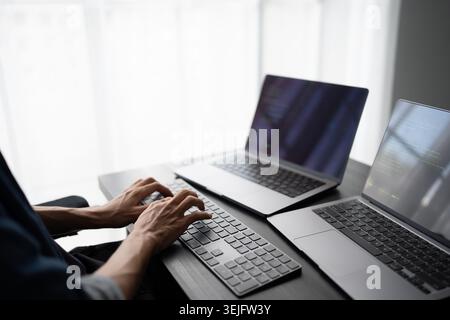 Asian man software engineer Working on Computer at office desk for writing program code IT Software Engineer finding errors tech support devops creati Stock Photo