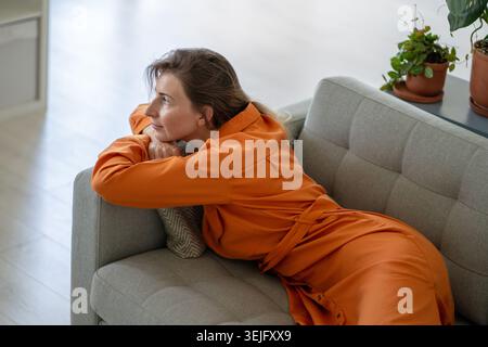 Relaxed middle-aged woman dreaming, fantasizing savoring memories lying comfortably on home couch Stock Photo