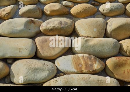 Close-up texture of smooth, naturally shaped river stones and pebbles forming a decorative surface or background pattern. Stock Photo