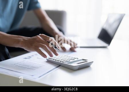 Man Managing Personal Finances Budget Household Expenses and Calculating Taxes with Calculator on the Table at Home. Stock Photo