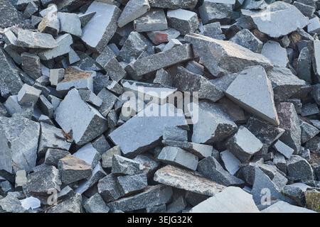 Pile of broken grey granite stone fragments, showing rough texture and irregular shapes. Raw material for construction or landscaping. Stock Photo