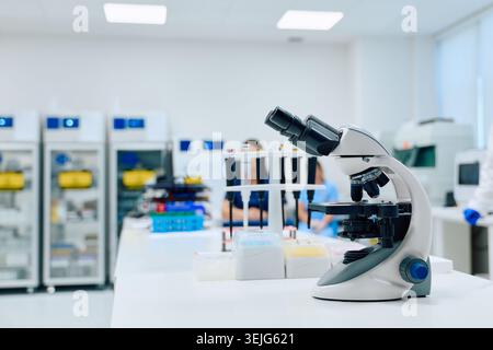 Microscope in a modern laboratory with scientists conducting research during daylight hours Stock Photo