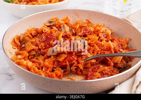 Bigos, Polish dish bigos, on the table, pan with stewed meat, with cabbage, chorizo sausages, mushrooms, homemade, without peopl Stock Photo