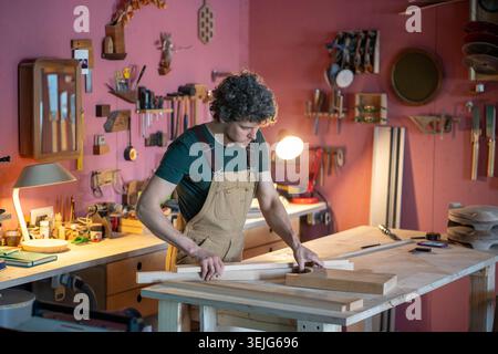 Man skilled carpenter creating unique furniture items for new work project in own carpentry workshop Stock Photo