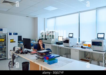 Laboratory setting featuring a female scientist engaged in research work amid advanced equipment and a clean workspace during da Stock Photo