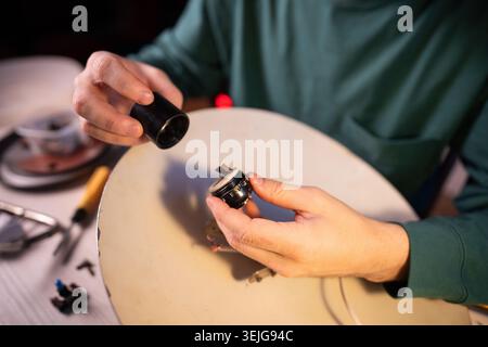 Man technician working on renovation of retro electric lamp at workshop, disassembling bulb socket. Stock Photo