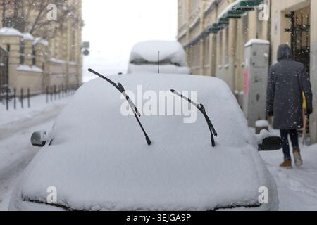 Car is fully covered with snow after snowstorm, windshield wiper raised up. Winter time in Europe Stock Photo