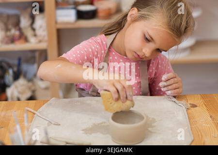 Child girl makes a cup of clay crafts pottery school Stock Photo