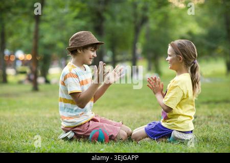 Two children brother and sister play sitting on the grass Stock Photo