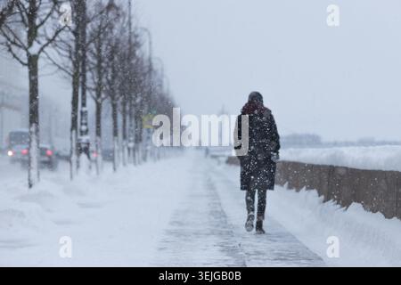 Silhouette of woman walking on street during snowfall. Heavy blizzard in European city Stock Photo