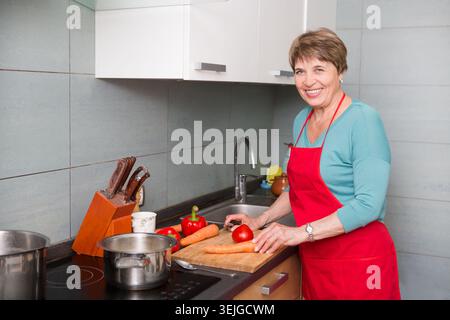 Happy elderly woman cooking  in kitchen at home Stock Photo