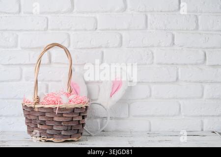 Easter background with eggs in basket and bunny ears on white brick wall Stock Photo