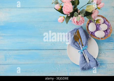 Easter table setting, eggs with cutlery on plate on table decorated for Easter, top view flat lay Stock Photo