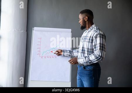 Flip chart displaying hand-drawn blue and red trend lines on easel in meeting room. Presentation, data, graph, analytics, confer Stock Photo
