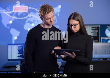 Young professionals analyzing cyber threats on a tablet in a SOC environment Stock Photo