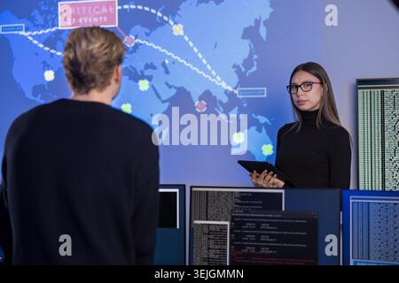 Team working in a cybersecurity operations center with digital monitoring tools Stock Photo