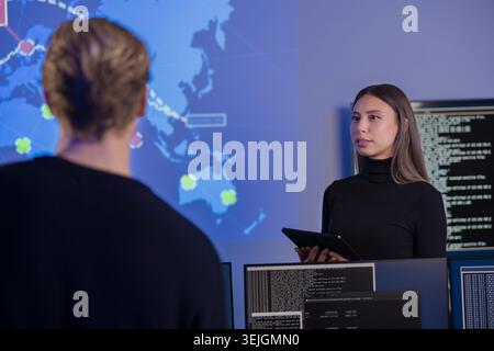 Team analyzing global cybersecurity data on advanced systems in monitoring center Stock Photo