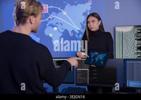 Cybersecurity analysts discussing threat detection strategies in the SOC control room Stock Photo