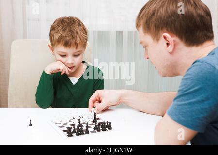 Father and son are playing chess while spending time Father and son are playing chess while spending time together at home. inte Stock Photo