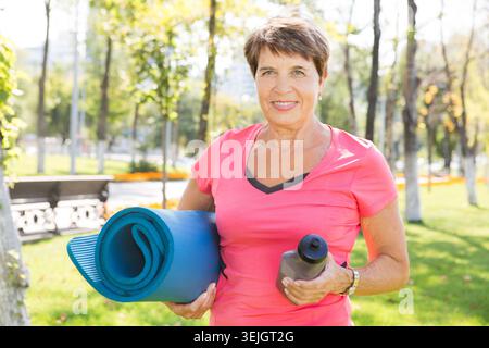 Elderly woman doing exercises outdoors Stock Photo