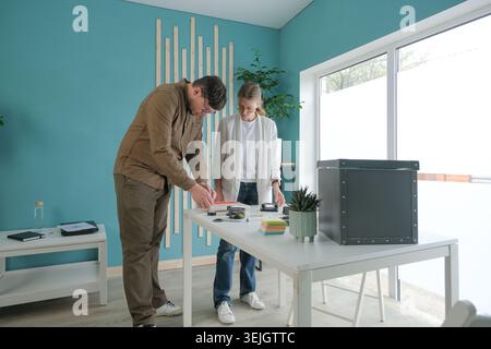 Millennial man and woman working in small office discussing documents Stock Photo