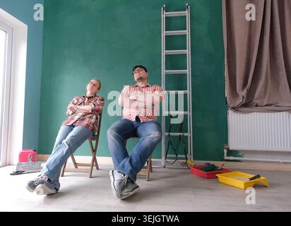 Happy couple renovating new house apartment , sitting on the chair and looking at the new house style Stock Photo