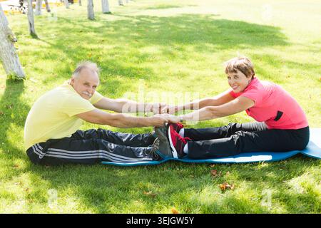 Happy elderly seniors couple exercising in park Stock Photo