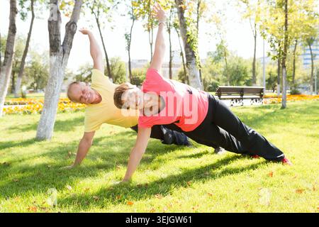 Happy elderly seniors couple exercising in park Stock Photo