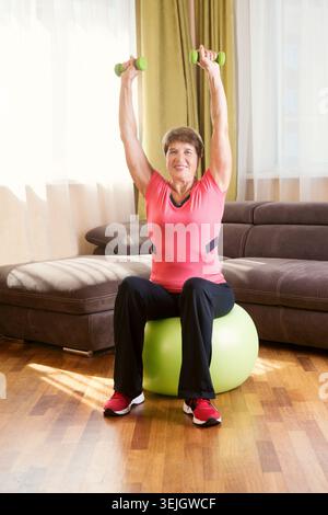 Cheerful senior lady exercising with dumbbells in the home Stock Photo