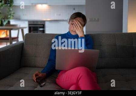 Young woman having headache looks with tired expression after working on business project at home Stock Photo