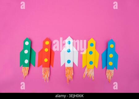 Top view of flying multi-colored rockets from paper on a color background Stock Photo