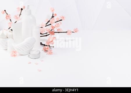 Cosmetic, beauty products for makeup, cleansing skin in white bottles, spring pink sakura flowers toiletry on table in soft ligh Stock Photo