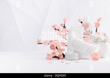 Cosmetic, beauty products for makeup, cleansing skin in white bottles, spring pink sakura flowers toiletry on table in soft ligh Stock Photo