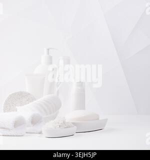 Cosmetic and beauty products for bath, spa in white bottles, toiletry - towels, bath salt, sponge on table in soft light white b Stock Photo