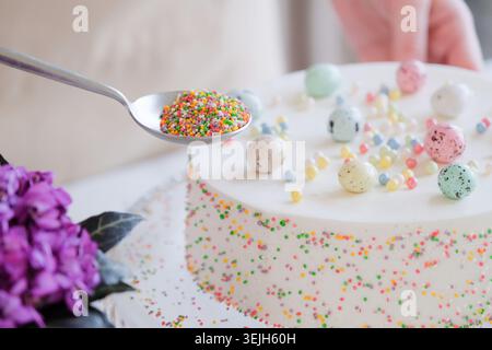 Young woman making Easter cake in pastel colors in the kitchen Stock Photo
