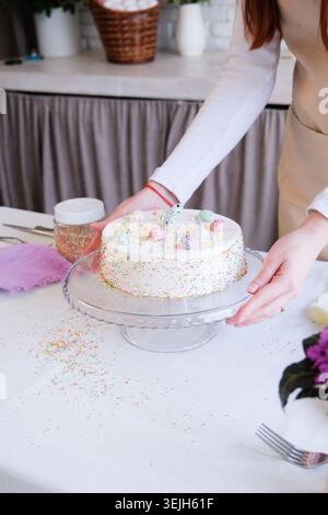Young woman making Easter cake in the kitchen, table setting Stock Photo