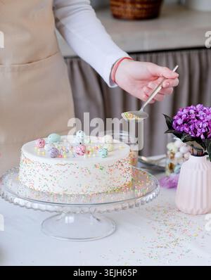Young woman making Easter cake in pastel colors in the kitchen Stock Photo