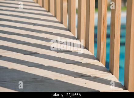 Abstract wooden bridge above the pool in day sunlight with deep shadows Stock Photo