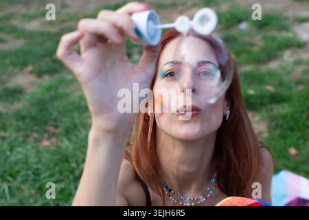 Woman blowing bubbles celebrating diversity and pride outdoors Stock Photo