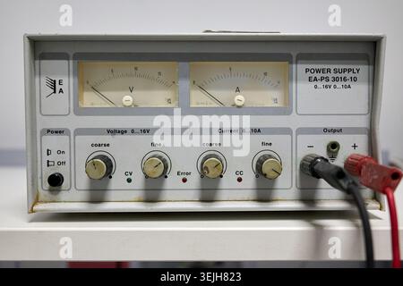 Laboratory laboratory DC power supply unit with analog voltage and current meters on the front panel. Stock Photo