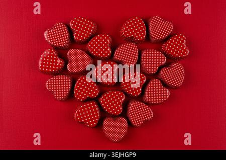Heart of red candy hearts on deep red paper background. Valentine day card. Stock Photo