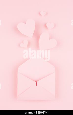 Valentines day background of pink paper envelop and stream soar small hearts on pink paper background. Stock Photo