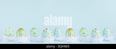 Stylish easter banner - blue easter eggs with gold design in white nest in row on blue background. Stock Photo