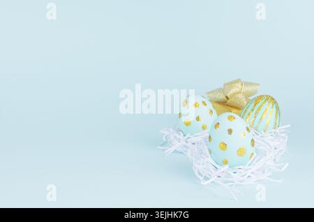 Blue easter eggs with gold glitter design, golden gift box on blue background, copy space. Stock Photo