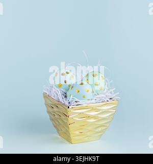 Fashion easter background - blue eggs with golden dots in golden bowl on blue color, square. Stock Photo