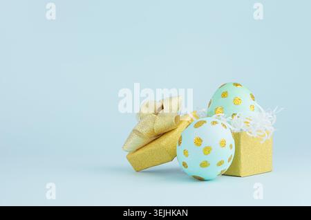 Stylish easter background with blue easter eggs with gold dots and gift box on blue background. Stock Photo