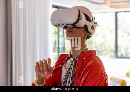 African American man standing in room wearing VR headset red button-up shirt and striped scarf. Technology, innovation, comfort, lifestyle, contempora Stock Photo