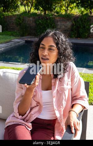 At home on a cushioned sofa, a young African American woman enjoys a ...