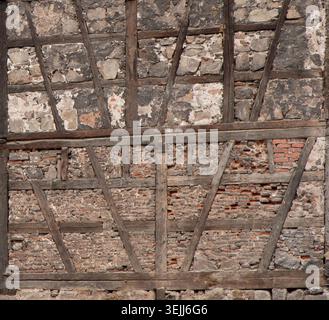 Old rustic half-timbered wall texture with dark weathered wooden beams, ancient stone, and brick masonry background. Stock Photo