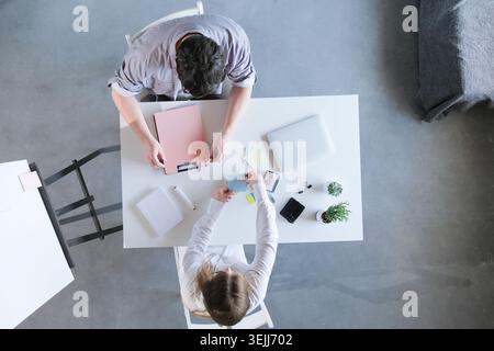 Millennial man and woman working in small office discussing documents, top view Stock Photo